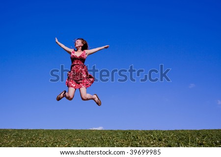 Young woman jumping for joy on a hillside in summer