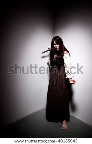 A cornered woman prepares to defend herself with a dagger