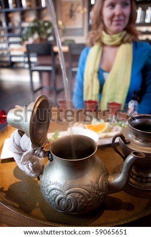 Woman watching her waiter pour water for mint tea