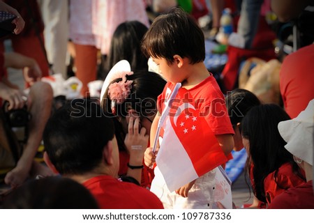 SINGAPORE - AUGUST 9: An unidentified chinese boy waving flag during Singapore National Day Parade (NDP) 2012 on August 9, 2012 in Singapore. Theme for NDP 2012 is  Loving Singapore, Our Home.
