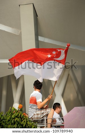 SINGAPORE - AUG 9: An unidentified chinese man waving flag during Singapore National Day Parade 2012 on Aug 9, 2012 in Singapore. Theme for National Day Parade  2012 is Loving Singapore, Our Home.