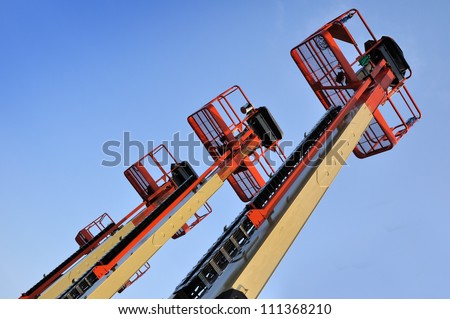 Close up of industrial boom lift basket against a blue sky.