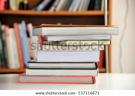 Stack of Education books on table in library, selective focus.