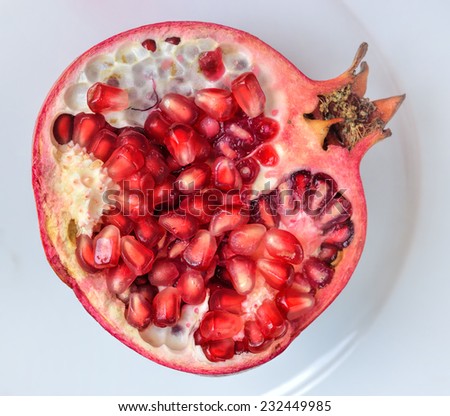 Close up of fresh ripe juicy pomegranate fruit on the white plate isolated on white background, selective focus.