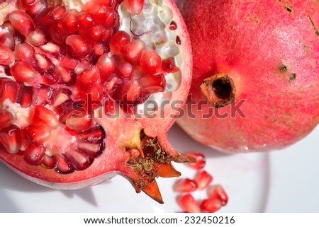 Close up of fresh ripe juicy pomegranate fruit on the white plate isolated on white background, selective focus.