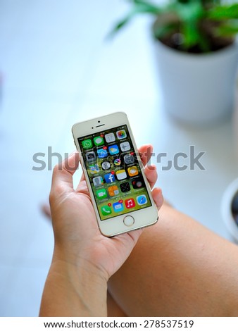SEMBAWANG, SINGAPORE - MAY 17, 2015: Woman holding white Apple iPhone 5S. Social media are trending and both business as consumer are using it for information sharing and networking.
