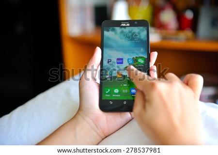SEMBAWANG, SINGAPORE - MAY 17, 2015: Woman holding brand new Asus Zenfone 2. Social media are trending and both business as consumer are using it for information sharing and networking.