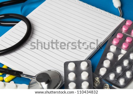Medical equipment: stethoscope, thermometer and medicine on blue