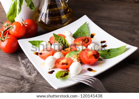 Caprese salad: tomato, mozzarella, basil leaves with olive oil and balsamico