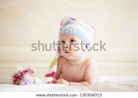 Five-month baby in crochet hat lies on the bed