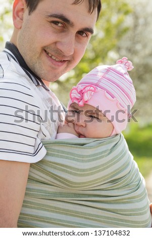 Young father with his five months daughter in sling