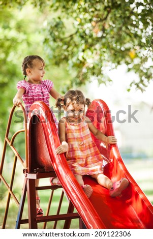 Two preschool girls on the slide at the playground