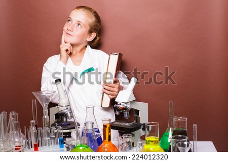 Thoughtful schoolgirl standing near blackboard in the laboratory classes in chemistry