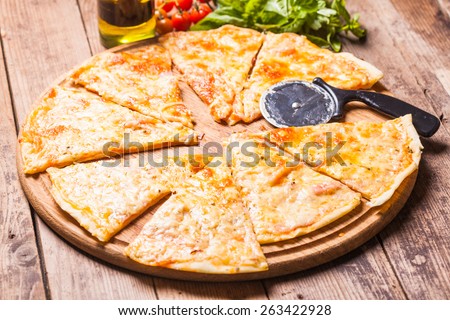 Pizza Margarita on the wooden board and pizza cutter