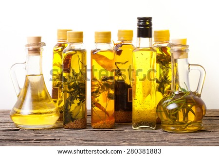 Assortment of spicy oils with herbs and spices in different bottles over white background