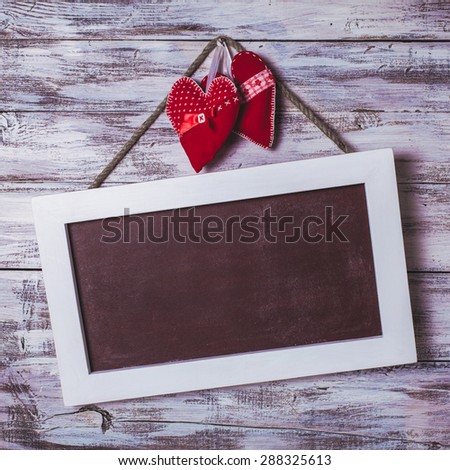Blank chalkboard on the shabby white background and red hearts for Valentine day greetings