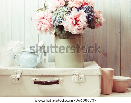 Flowers in a blue vintage can on white retro bag and kitchen earthenware