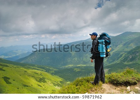 Man in montains with binocular and back pack look