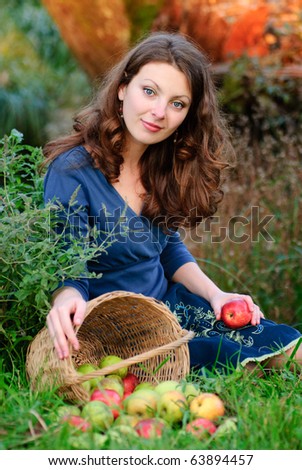 woman and apple crop in garden. Evening glow behind.