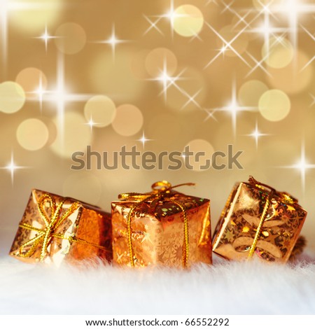Gold Christmas presents on white fur and background of defocused golden lights. Shallow DOF.