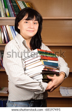 Young woman picking out several books for pleasure reading.
