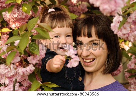 Mother and daughter in garden, under the sakura tree. Spring.