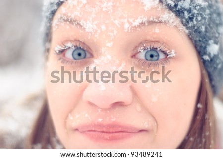 Girl\'s face under snow outdoors. Close up portrait