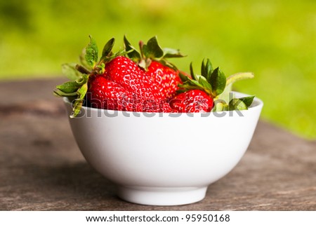 Strawberry with bowl on wooden table outdoor