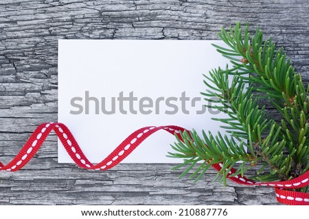 Christmas card: empty paper form with fir-tree branches and red tape on old wooden background