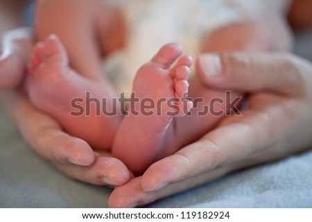 parent holding new born baby\'s feet, soft focus
