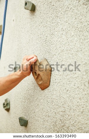 hand holding stone on rock climbing wall