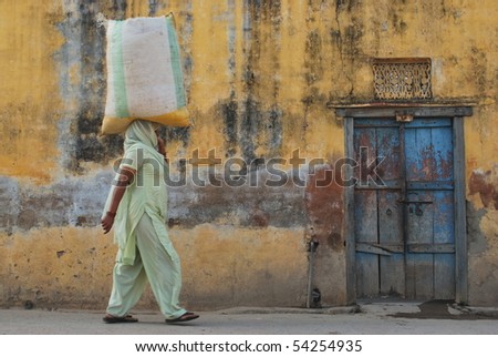 Woman holding bag on her head. Picture in taken in India.