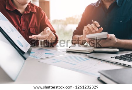 Two business people are calculating earnings financial costs of the company on desk at the office room.