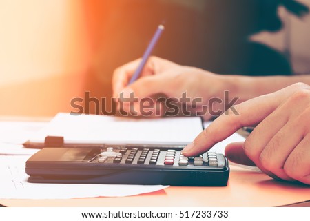 Close up young woman with calculator counting making notes at home, hand is writes in a notebook. Savings, finances, concept.