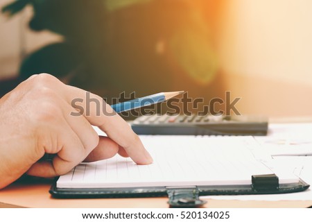 Man hand is holding pencil thinking about savings finance and calculator at  home.