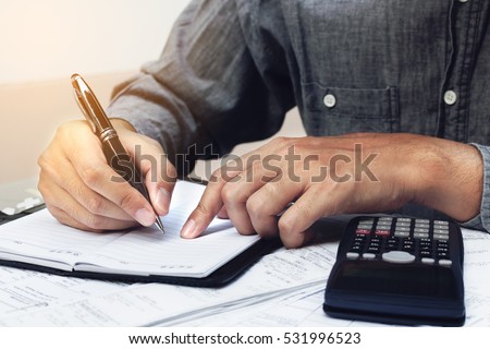 Finance concept. Man writing and make note about cost and expenses at home office.