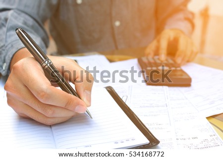 Businessman making finances with using calculator and writing note in office.