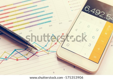 Data analyzing with calculator mobile phone and pen. from charts and graph to find out the result.