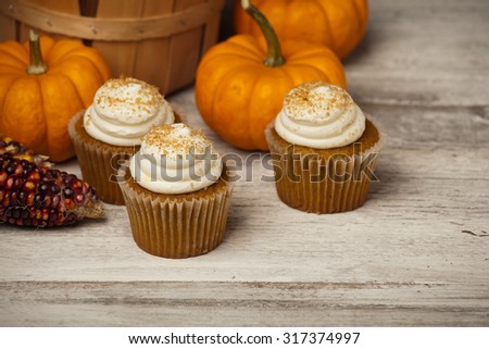 Pumpkin spice cupcakes and mini pumpkins in fall scene.