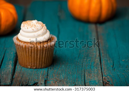 Pumpkin cupcake on blue background with mini pumpkin