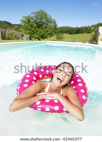 Woman floating in pink polka dot inner tube and laughing. Vertical.