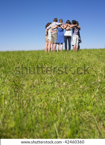 A group of people huddle in a field. Vertically framed shot.