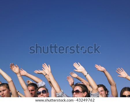 People with hands in the air, with only their faces visible. Horizontal.