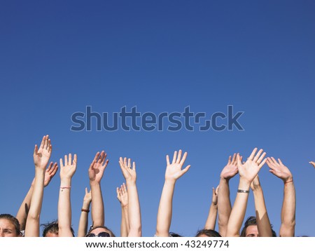 People with hands in the air, with only the tops of their faces visible. Horizontal.