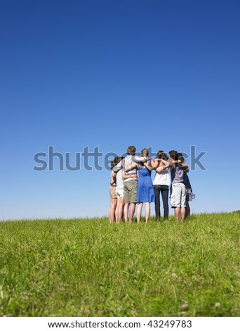 A group of people huddle in a field. Vertically framed shot.