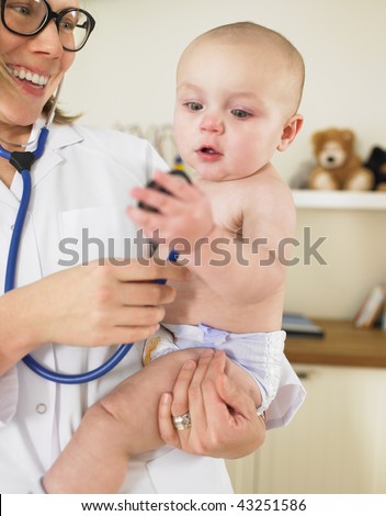 Baby examining stethoscope while being held by pediatrician. Vertically framed shot.