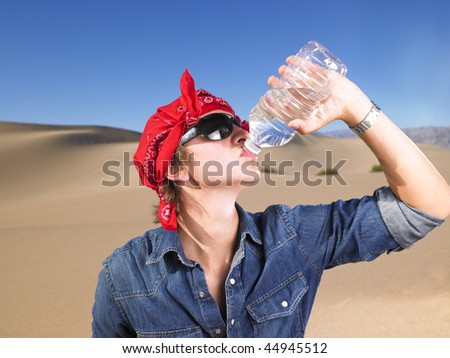 Young man in sunglasses wearing red bandana drinking a bottle of water. Horizontal shot.