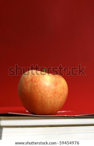 red apple resting on the book with chalk board as background