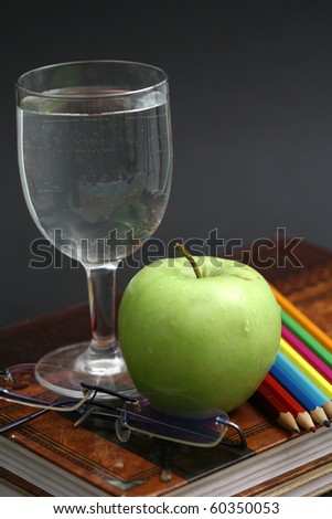 green apple resting on the book with chalk board as background