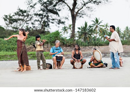 GOA, INDIA - NOVEMBER 08: Hippies playing music on Arambol beach on November, 08, 2011, Goa, India. At the Arambol beach people often sit and enjoy the setting sun, playing music, meditation, etc.